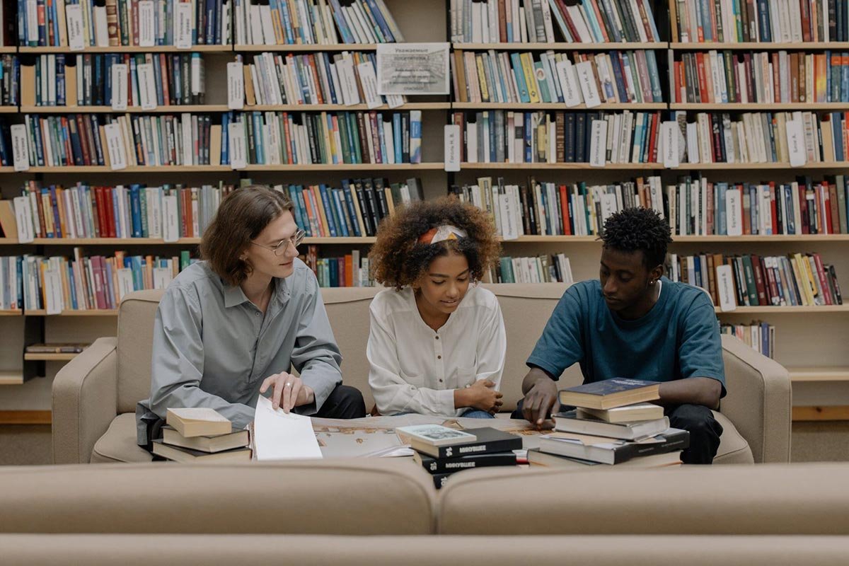 A group of 3 people studying languages in a library