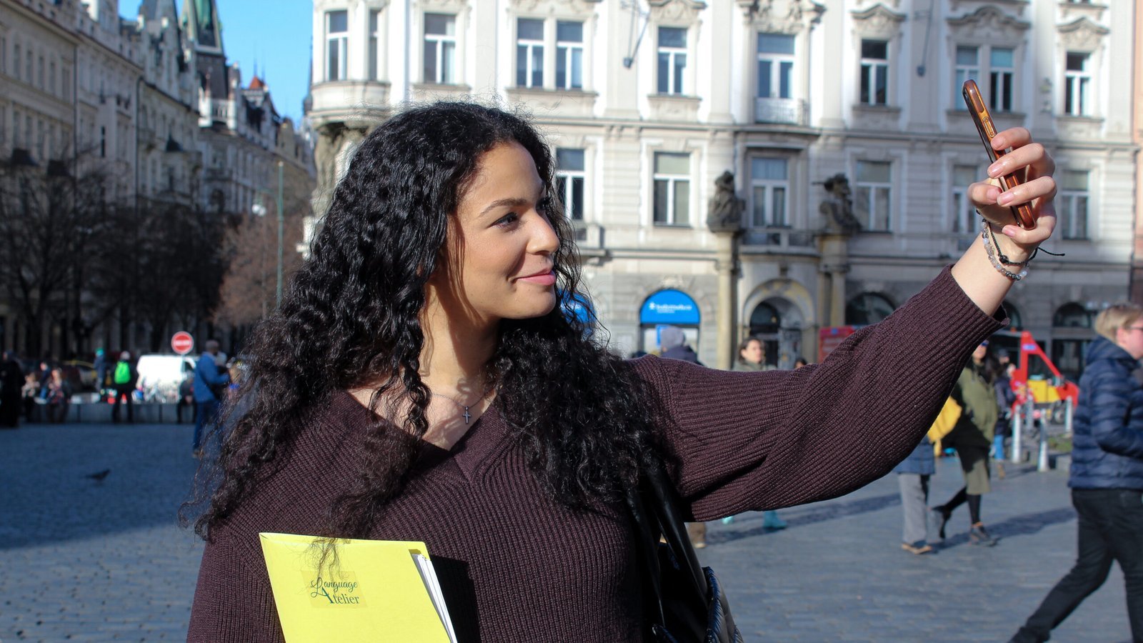 student-taking-selfie-outdoors-languageatelier Woman taking a selfie with Language Atelier notebook in city square