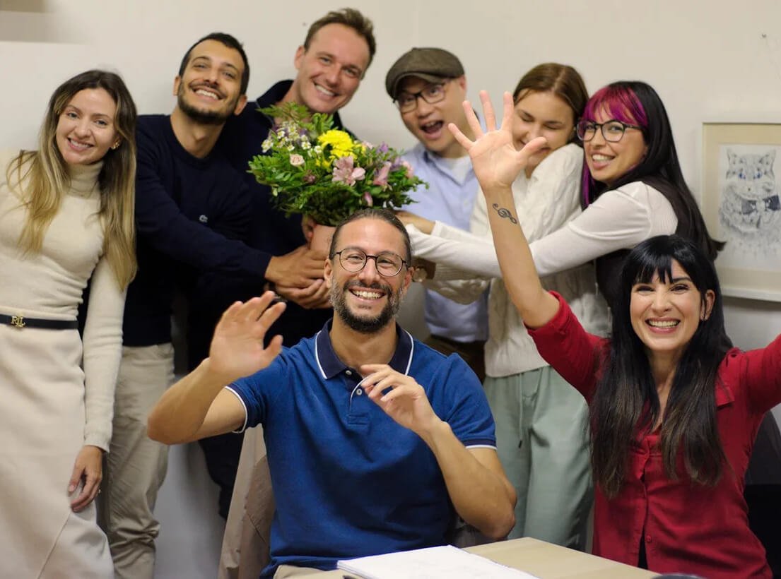 Smiling students waving together in a Language Atelier classroom